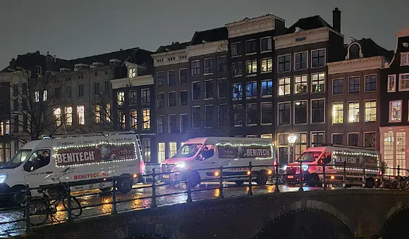 3 Benitech bussen met tekst 'prettige feestdagen' rijden op brug in Amsterdam