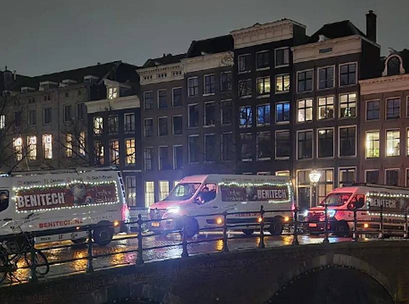 3 Benitech bussen met tekst 'prettige feestdagen' rijden op brug in Amsterdam