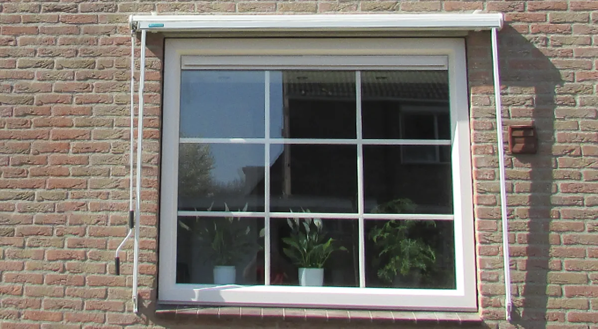 Klassiek kozijn met roedes en ventilatierooster in muur