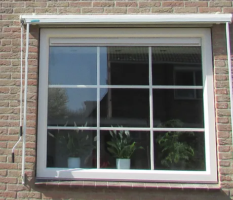 Klassiek kozijn met roedes en ventilatierooster in muur
