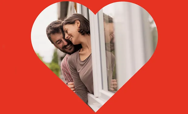 Man en vrouw leunen uit het raam en genieten van kunststof kozijnen omkadert met rood hart Valentijnsdag