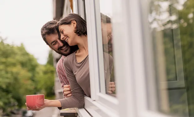 Man en vrouw leunen uit het raam en genieten van kunststof kozijnen