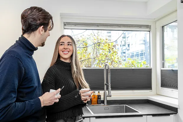 Keuken met kunststof kozijnen met man en vrouw met glas drinken in handen genietend. 