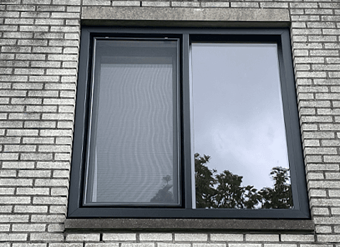 Antracietgrijs kunststof kozijn met twee ramen in gevel woning