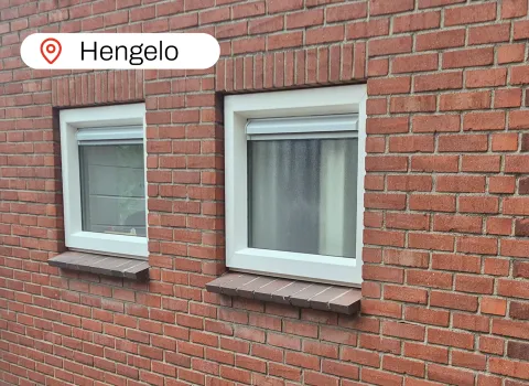 Witte kunststof kozijnen met ventilatierooster in stenen gevel