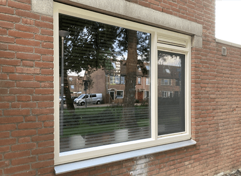 Kunststof kozijn met twee ramen en ventilatierooster in stenen gevel buiten
