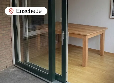 Openstaande groene kunststof schuifpui in woning in Enschede