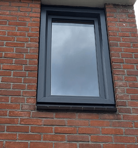 Antracietgrijs kunststof kozijn in stenen muur buiten