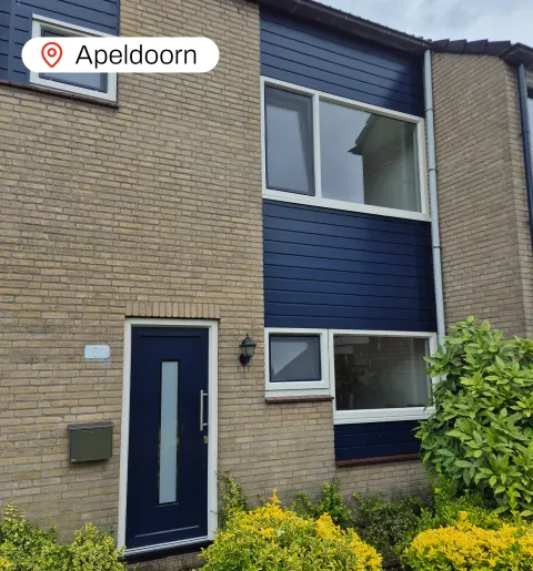Voorgevel woning met blauwe en witte kunststof voordeur, kunststof gevelbekleding en kunststof kozijnen