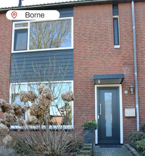 Voorgevel woning Borne met witte kunststof kozijnen en antracietgrijze kunststof voordeur, gevelbekleding en ramen
