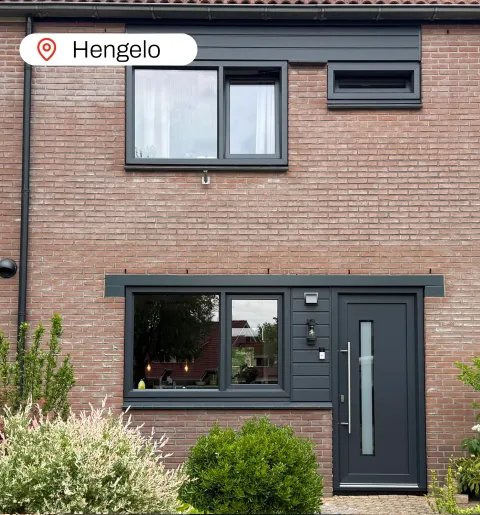 Voorgevel woning met antracietgrijze kunststof kozijnen en kunststof voordeur