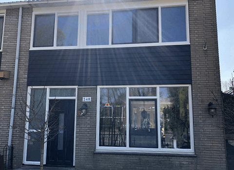 Voorgevel woning Rotterdam met staalblauwe en witte kozijnen, voordeur en Keralit gevelbekleding in kunststof