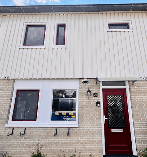 Voorgevel woning met rode kunststof voordeur en kunststof kozijnen