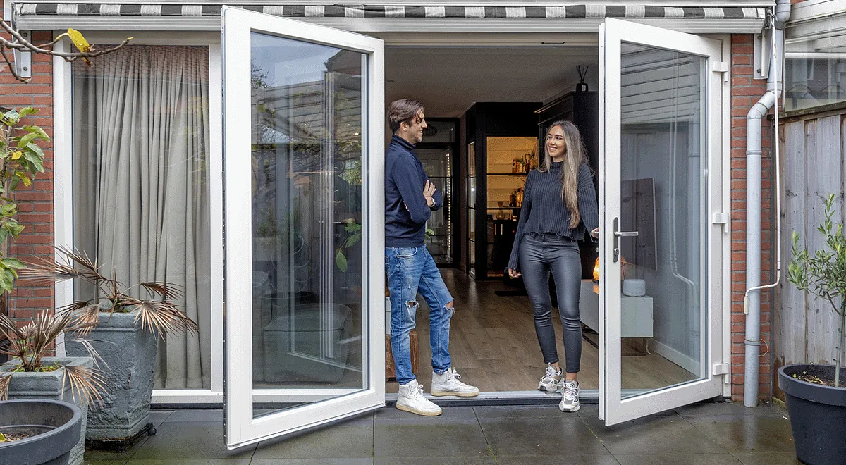 Openstaande kunststof openslaande deuren met genietende man en vrouw in deuropening