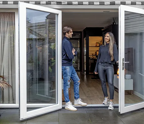 Openstaande kunststof openslaande deuren met genietende man en vrouw in deuropening