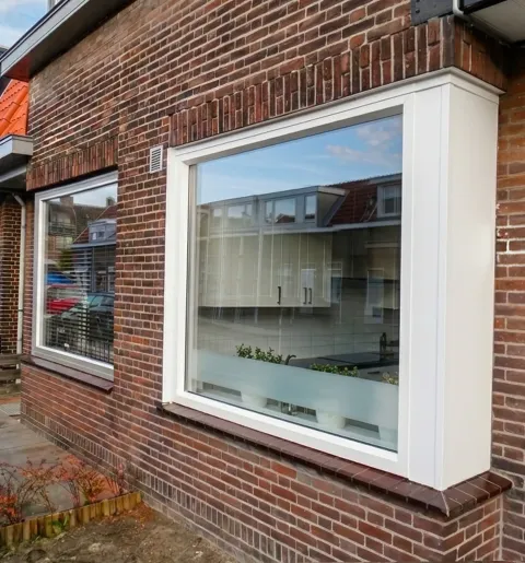 Wit kunststof bloemkozijn dat naar voren komt in de voorgevel