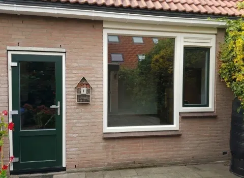 Achtergevel met groene kunststof achterdeur en naastgelegen kozijn