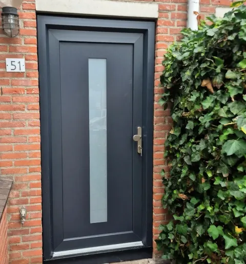 Antracietgrijze kunststof voordeur in de voorgevel van een woning