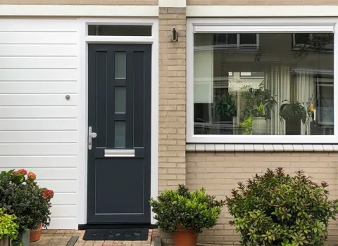 Voorgevel woning met kunststof voordeur, gevelbekleding en vast raam