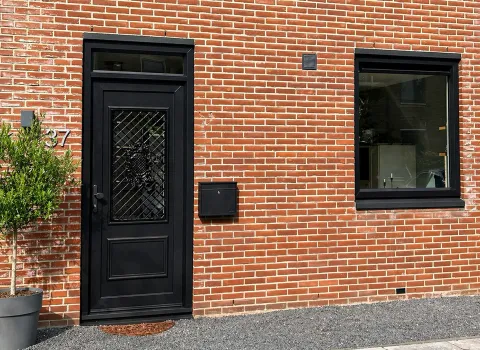 Voorgevel woning beneden met kunststof voordeur en kunststof kozijn vast raam