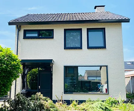 Voorgevel moderne vrijstaande woning met witte gevel en zwarte kunststof kozijnen