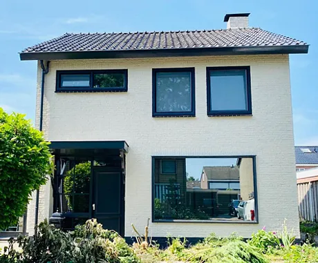 Voorgevel moderne vrijstaande woning met witte gevel en zwarte kunststof kozijnen