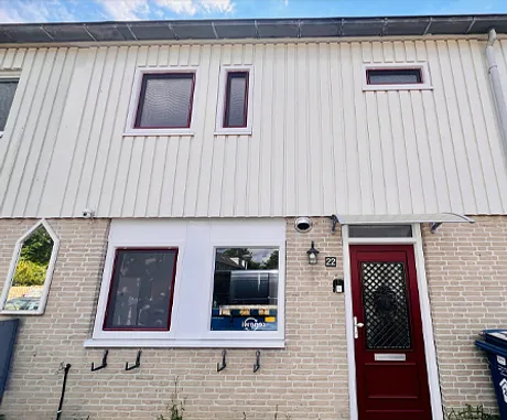 Voorgevel woning met kunststof kozijnen en kunststof voordeur wijnrood en wit