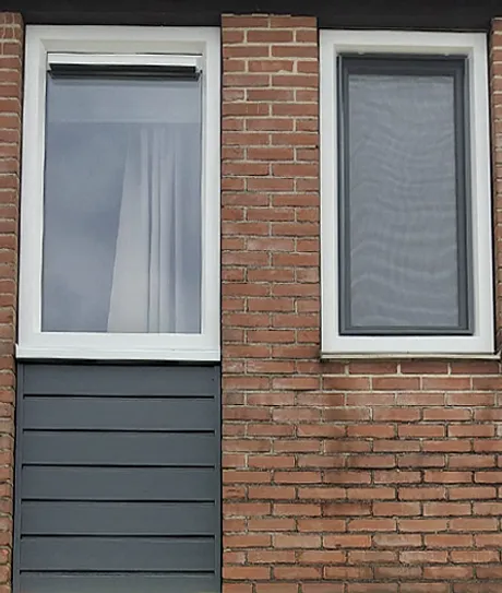 Twee smalle kunststof kozijnen en kunststof gevelbekleding in gevel woning