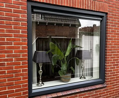 Antracietgrijs kunststof kozijn in donkerrode bakstenen muur