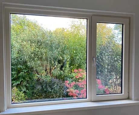 Kunststof kozijn met groot vast raam en draaikiepraam met uitzicht op de tuin