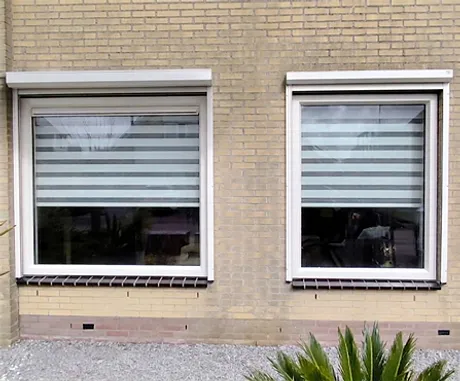 Voorgevel woning met twee witte kunststof kozijnen en rolluiken