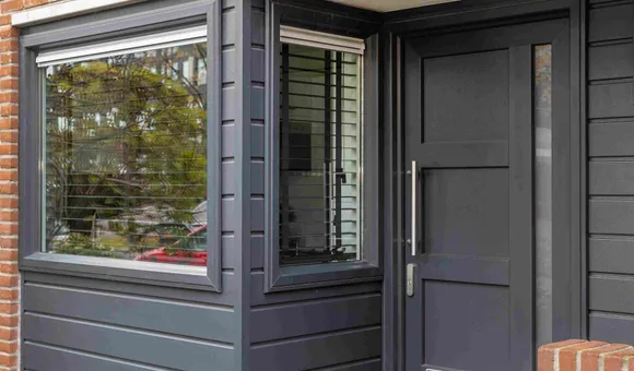Begane grond voorgevel woning met antracietgrijze kunststof kozijnen, gevelbekleding en voordeur